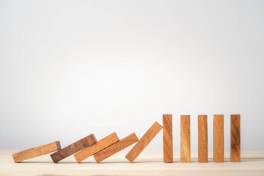Birçok tahta blok domino taşları tek bir tahta bloğa düşüyor direnç ve risk yönetimi kavramını durduruyor..