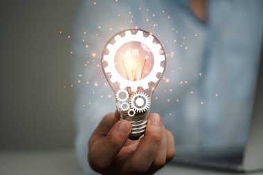 Mekanik teçhizatla parlayan ampulü tutan iş adamı yaratıcı düşünce ve yenilik kavramı.