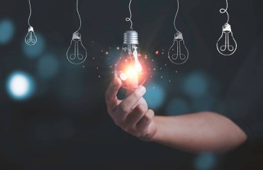 İş adamı, yaratıcı düşünce ve yenilik kavramı için elinde ışıldayan bir lamba tutuyor..