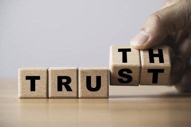 Güven ve Gerçeklik kelimelerini gösteren tahta bloklar, dürüstlüğü ve dürüstlüğü sembolize eden bir el düzenlemesi mektupları ile dürüstlük ve şeffaflığı simgeleyen iş konsepti bütünlüğü ve otantik iletişim için