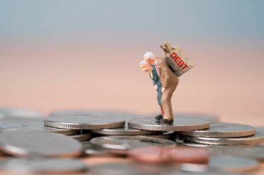 Emekli olduktan sonra borç çantası taşıyan emekli yaşlılar emeklilik sonrası maddi yük için birikmiş madeni paraların üzerinde duruyorlar. Emeklilik riski ve kişisel finans sorunu kavramı.