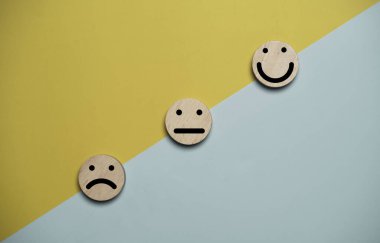 Ahşap duygu simgeleriyle dolu müşteri memnuniyeti konsepti. Renkli arka planda mutludan mutluya. Hizmet kalitesi iyileştirme, geribildirim derecelendirme ve kopyalama alanı ile deneyim değerlendirme teması.