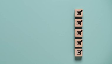 Tahta bloklar ile kontrol listesi ve görev tamamlama kavramı dikey olarak işaretleri gösterir. Kalite kontrol güvencesi, denetim süreci, proje yönetimi ve ticari uyum iş akışı stratejisi.