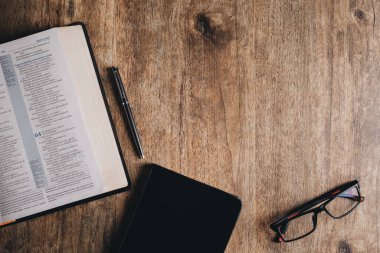 Open Bible and notebook on a wooden desk.