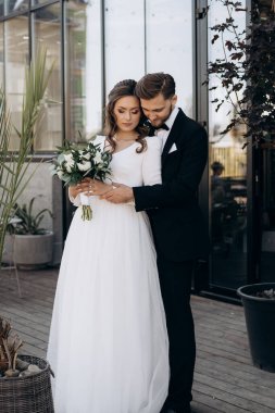 Damat geline sarılıyor. Palmiye yapraklarının yanında yeni evlenmiş şirin bir Avrupalı 'nın portresi. Düğün açık havada.