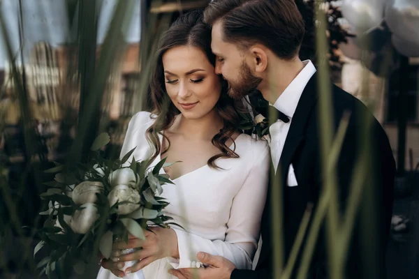 Damat güzel gelini yanağından öpüyor. Yeni evli şirin bir çiftin portresi mi? Erkek bir kadını öper.