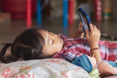 Asyalı öğrenci odadaki kağıda renkler çiziyor ve boyuyor. Evden eğitim, sosyal uzaklık, çocuk ve eğitim konsepti. 2-3 yaş arası çocuk portresi.