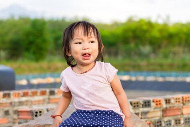 1 yıl 4 aylık bir kızın portresi. Çocuk parkında oyuncakla oynarken Asyalı kız ağlıyor. Bebek konseptinin ifade ve duyguları.