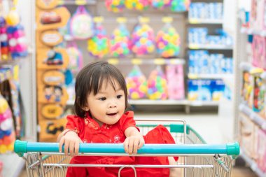 2 yaşındaki bir bebeğin portresi. Mutlu Asyalı çocuk süpermarkette alışveriş arabasında oturuyor..