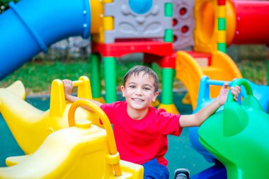 Kırmızı tişörtlü mutlu bir çocuk lunaparkta eğleniyor. Mutlu bir çocuğun portresi