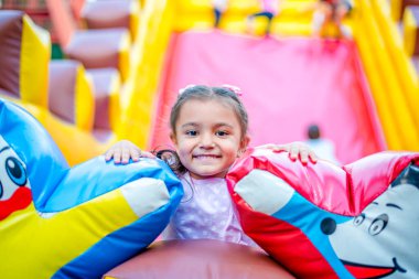 Küçük mutlu kız lunaparkta oynuyor. Tatildeki neşeli çocuk. Çekici bir kızın portresi