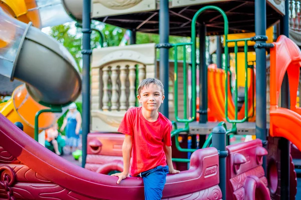 Kırmızı tişörtlü mutlu bir çocuk lunaparkta eğleniyor. Mutlu bir çocuğun portresi