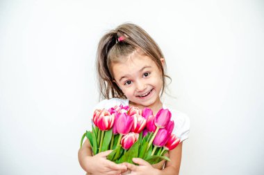 Beyaz arka planda bahar laleleri olan gülümseyen güzel bir kızın portresi. Uluslararası Kadınlar Günü. Kız 5 yaşında, Kafkasyalı. İzole edilmiş.