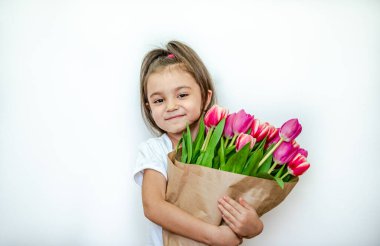 Beyaz arka planda bahar laleleri olan gülümseyen güzel bir kızın portresi. Uluslararası Kadınlar Günü. Kız 5 yaşında, Kafkasyalı. İzole edilmiş.