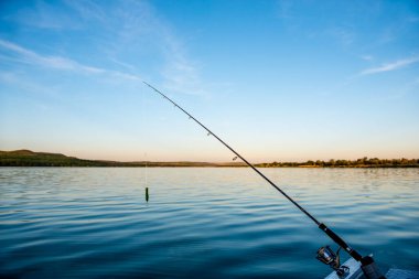 Olta oltası yakın plan halatla dönüyor. Gün batımında balıkçılık günü için olta tutacağında olta kamışı. Çubuk halkaları. Balık oltası. Dönen balık makarası.