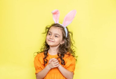 Sarı arka planda paskalya tavşanı kulakları olan neşeli bir kız.
