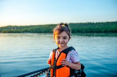 Teknede yürürken can yeleği giymiş küçük mutlu kız. 