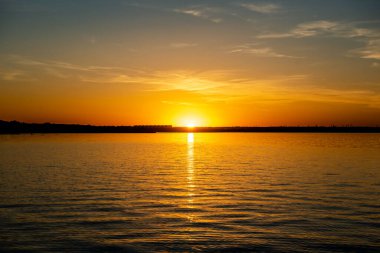 Rusya 'nın güneyindeki küçük bir kasabada, bir gölün üzerinde gün batımının erken saatlerinde güneş suya yansıyor.. 