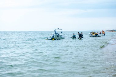 Bugaz Spit. Rusya, Haziran 2021. Oksijen tüpleriyle tam teçhizatlı bir grup dalgıç Karadeniz kıyısından suya giriyor. Dalgıçlar motorlu bir tekneye binmeye hazırlanıyorlar. 