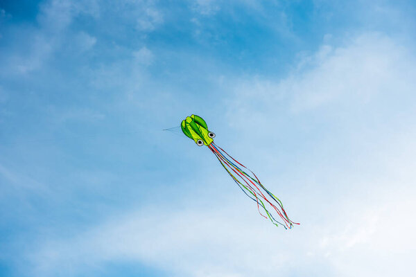 kite in hand on blue sky in sunny weather and wind. Kite flying in summer with copy space. Freedom. Summer games and fun