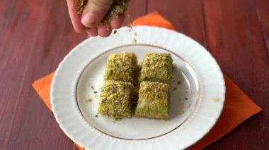 Yavaş hareket eden şam fıstıkları baklava üzerine dökülür.
