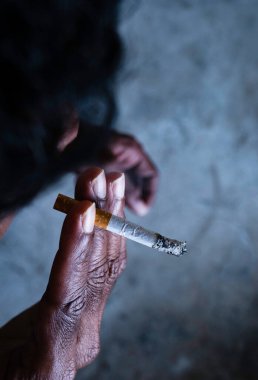Closeup of cigarette butt with poor man hand