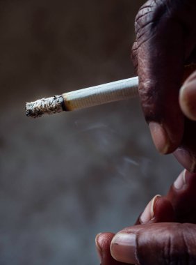 Closeup of cigarette butt with poor man hand