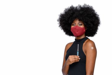 Yüzünde bir gülümseme ile Covid-19 'a karşı koruyucu maske takan siyah bir genç beyaz arka planda izole edilmiş aşı markasını gösteriyor.