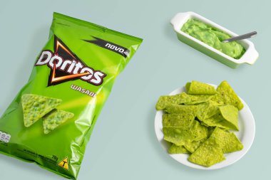 So Paulo, Brazil - 13, July, 2021packaging of salty wasabi doritos and a plate with salty foods, on a green background.