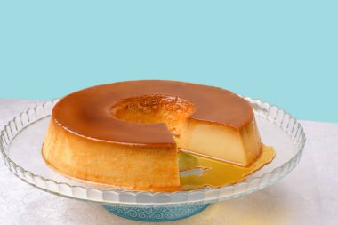 Mavi arka planda şeffaf bir tabakta puding.