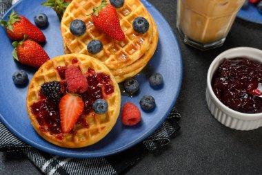 Kahvaltıda taze kırmızı böğürtlenli lezzetli waffle ve buzlu kahve..