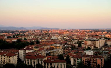  Gün batımında Bergamo (İtalya) Panoraması. Kırmızı kiremitli çatıları olan binalar. Uzakta dağlar