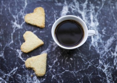 Bir fincan sade kahve ve kalp şeklinde kurabiye..