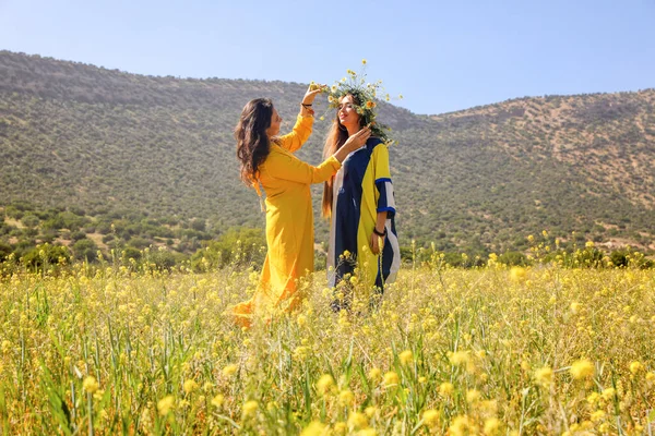 Two women with wreaths on their heads in a field.