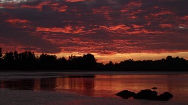 Sahilde gün batımı yansıması. Kırmızı ve altın rengi bulutlar. Turuncu renkli günbatımı ve dalgalar..