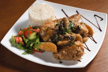 Kızarmış et parçaları, patates ve fesleğenle birlikte pirinç ve salata ile birlikte.