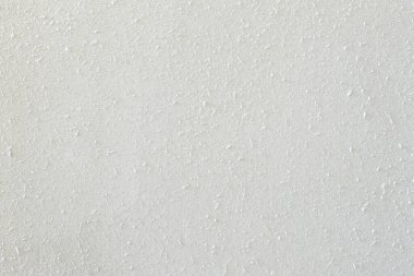 Beton duvarın soyut beyaz dokusu, küçük sıçrama detayları ve çimento çıkıntıları ile yakın plan