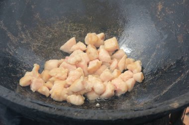 Çiğ kuzu eti parçaları siyah bir kazanda kızartılıyor, yemek pişiriyorlar.