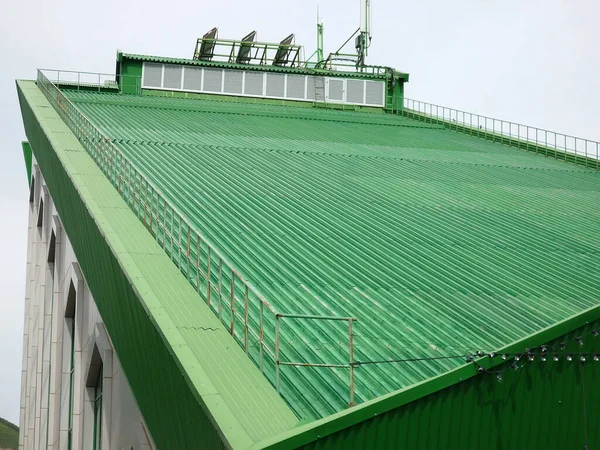 Sloping green roof of the building with a mobile communication antenna