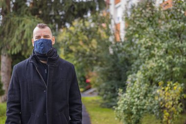 Bir adam damlayan yağmurda Macaristan 'ın küçük bir şehrinde maske takarak yürür.
