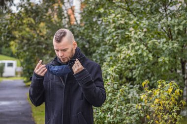 Macaristan 'ın küçük bir şehrinde damlayan yağmurda bir adam maskesini takıyor.