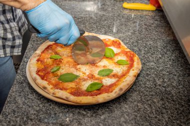 Margherita pizzasını yerel bir pizza ve jiroskop restoranında kesen bir adam.