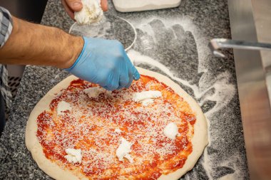 Bir adam yerel bir pizza ve jiroskop restoranında margherita pizza yapıyor.