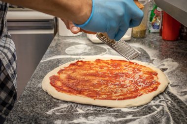 Bir adam yerel bir pizza ve jiroskop restoranında margherita pizza yapıyor.