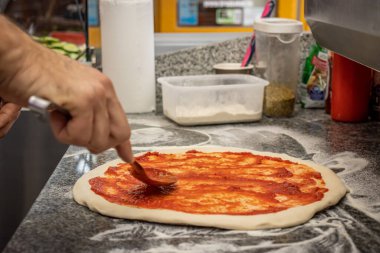 Bir adam yerel bir pizza ve jiroskop restoranında margherita pizza yapıyor.