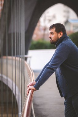 Olgun sakallı adam gün batımında Madrid Köprüsü 'nün korkuluklarına yaslanıyor..