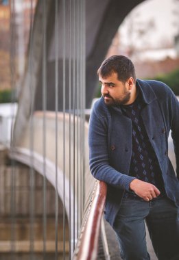 Olgun sakallı adam gün batımında Madrid Köprüsü 'nün korkuluklarına yaslanıyor..