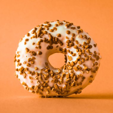 Turuncu arka planda bademli beyaz çikolatalı çörek..