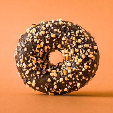 Turuncu zemin üzerinde badem olan çikolatalı çörek..