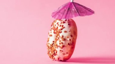 Badem soslu beyaz çikolatalı çörek ve pembe arka planda zum yapıp duran dekorasyon şemsiyesi..